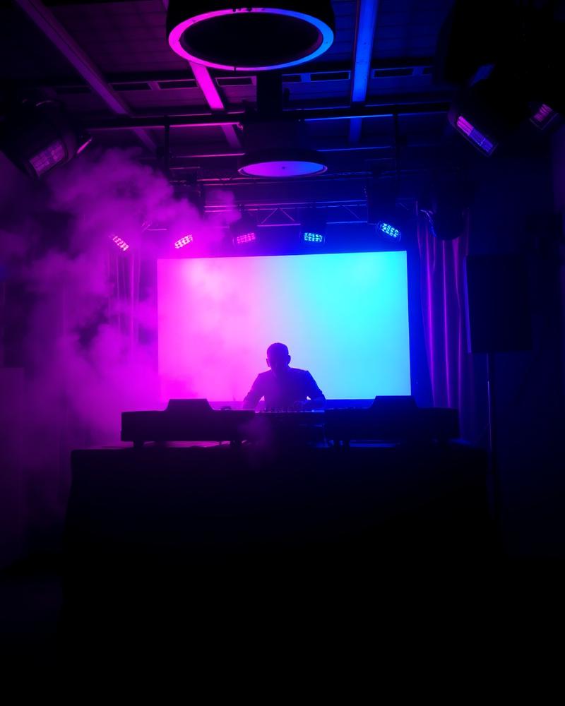 DJ playing on the main stage in pink and cyan light